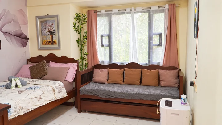 The cozy bed and wooden daybed beside a bright window